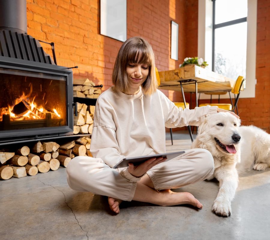 woman-sitting-relaxed-with-her-dog-floor-near-fireplace-using-digital-tablet-home (1)